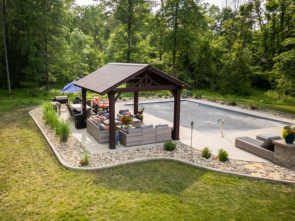 Backyard oasis with a gazebo, seating area, and swimming pool surrounded by greenery.