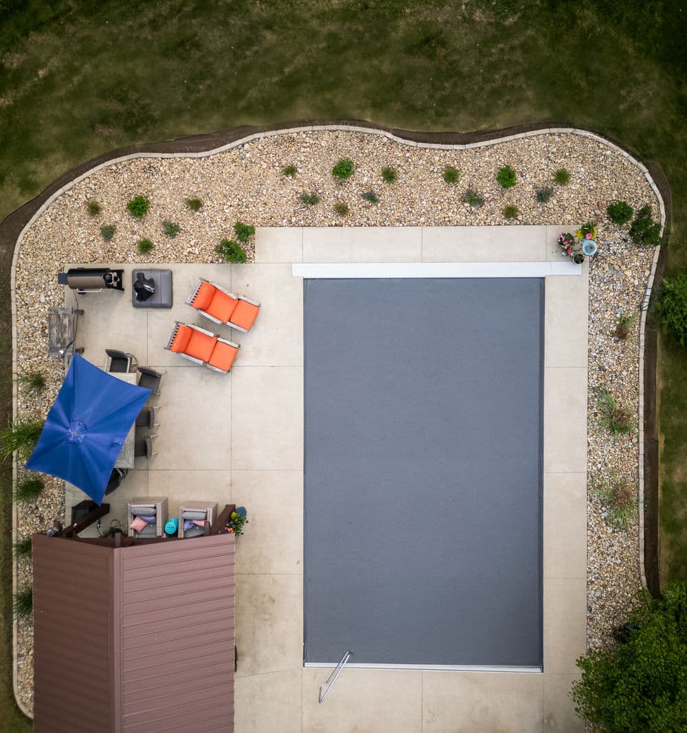Aerial view of a patio with a pool, lounge chairs, and landscaping around the edge.