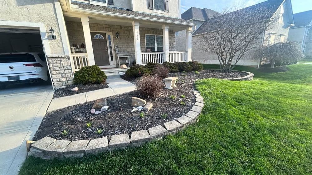 Front yard landscaping with stone border, flower beds, and a well-maintained lawn.